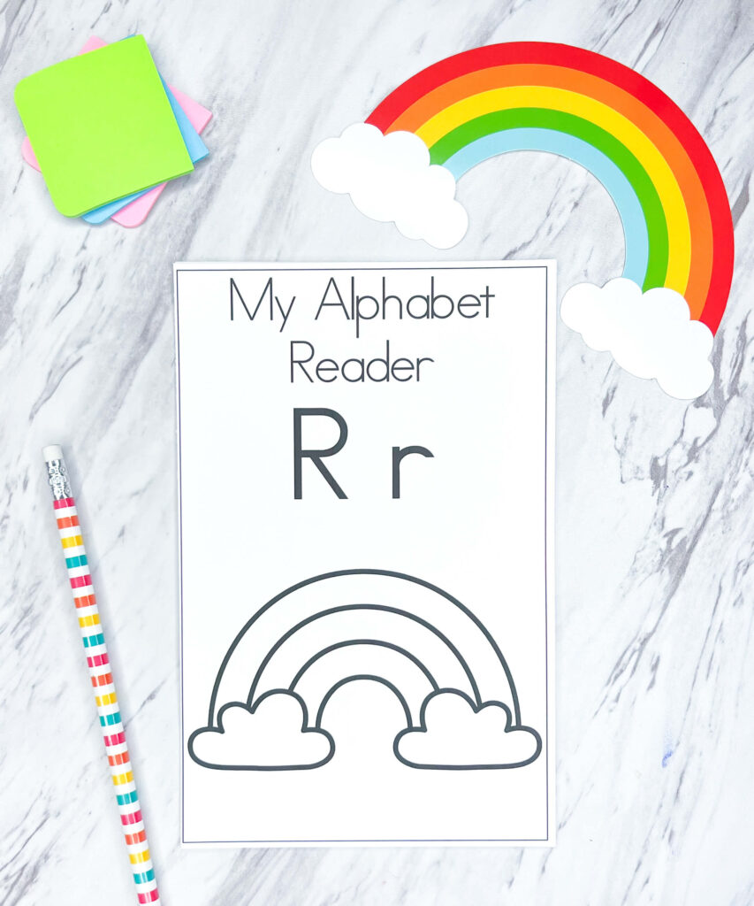 Image shows "R" alphabet reader with a pencil next to it and note pads in the top left corner. In the top right corner sits a cutout of a rainbow.