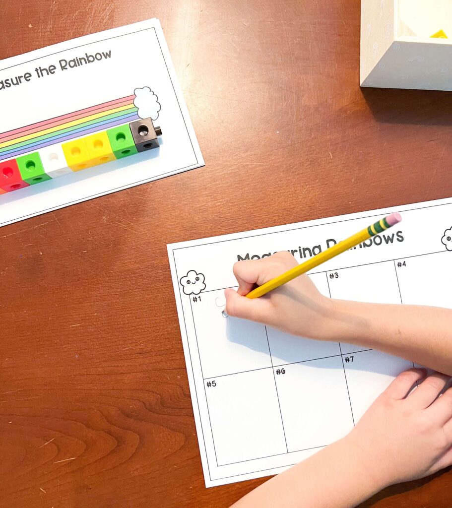 Image shows linking cubes measuring the rainbow and a child's hand is recording the number on to the worksheet