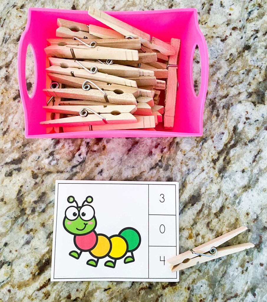 The image shows a task card with a caterpillar and numbers on the side of the card.  There is a clothespin laid out on the number 4 for the number of sections in the caterpillar.  In a pink box above the clip card there are clothespins. 